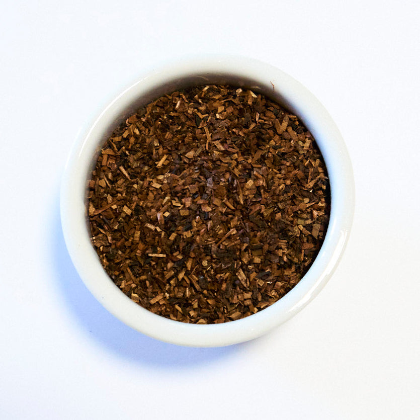 White bowl filled with dark brown leafy substance on a white background