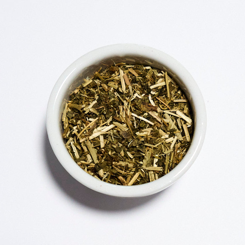 White bowl filled with dried herbs on a white background