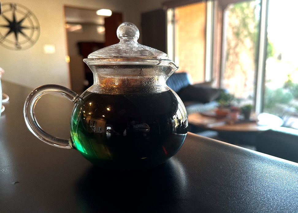 vibrant green colored tea in a clear teapot, zen home space in background