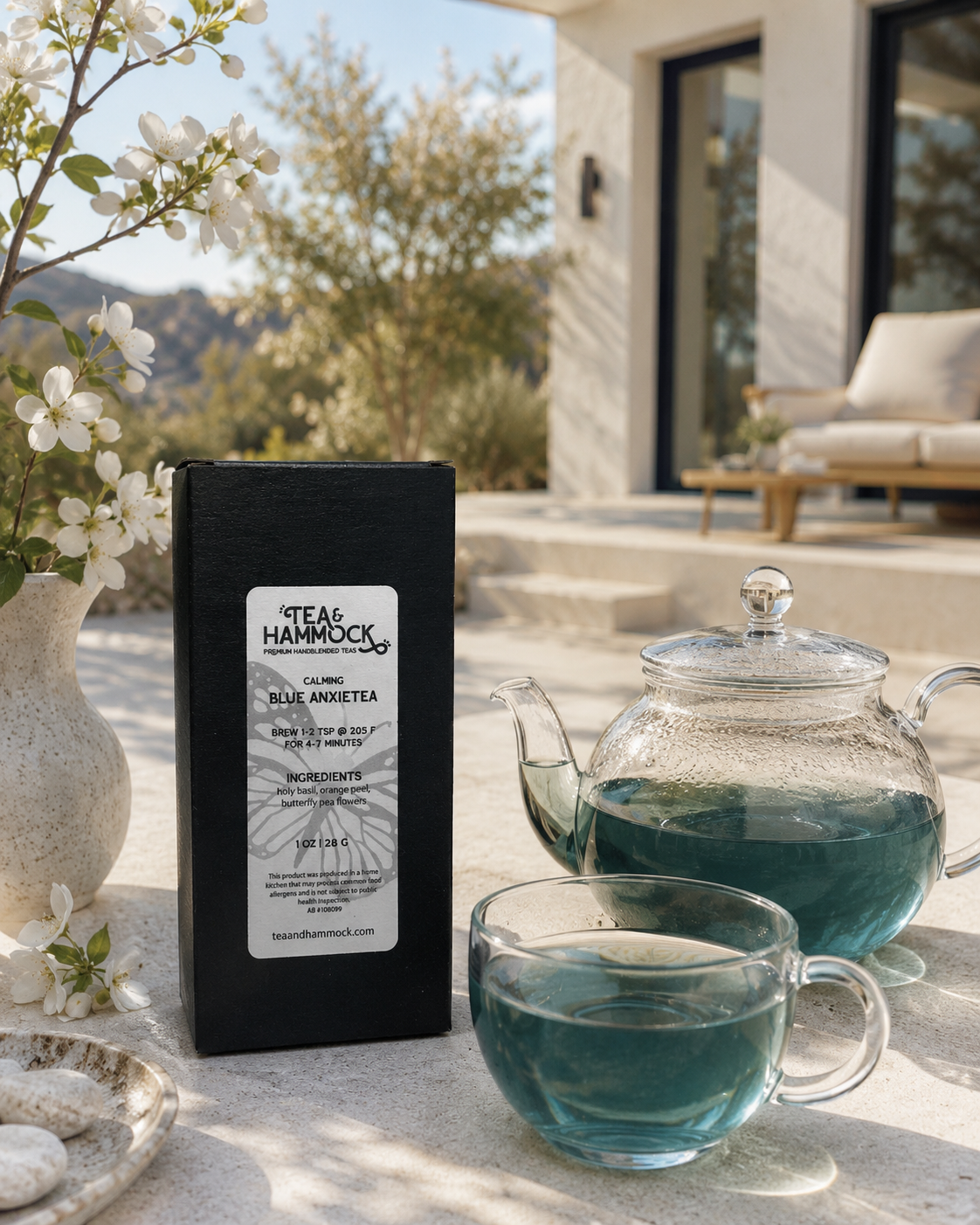Tea & Hammock Blue Anise Tea packaging with a teapot and cup on a table outdoors.