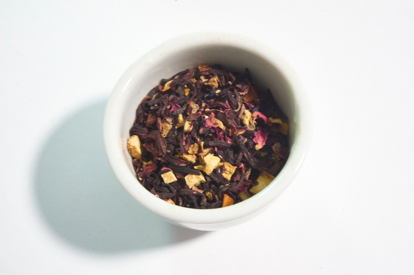 White bowl filled with dried tea leaves on a light background