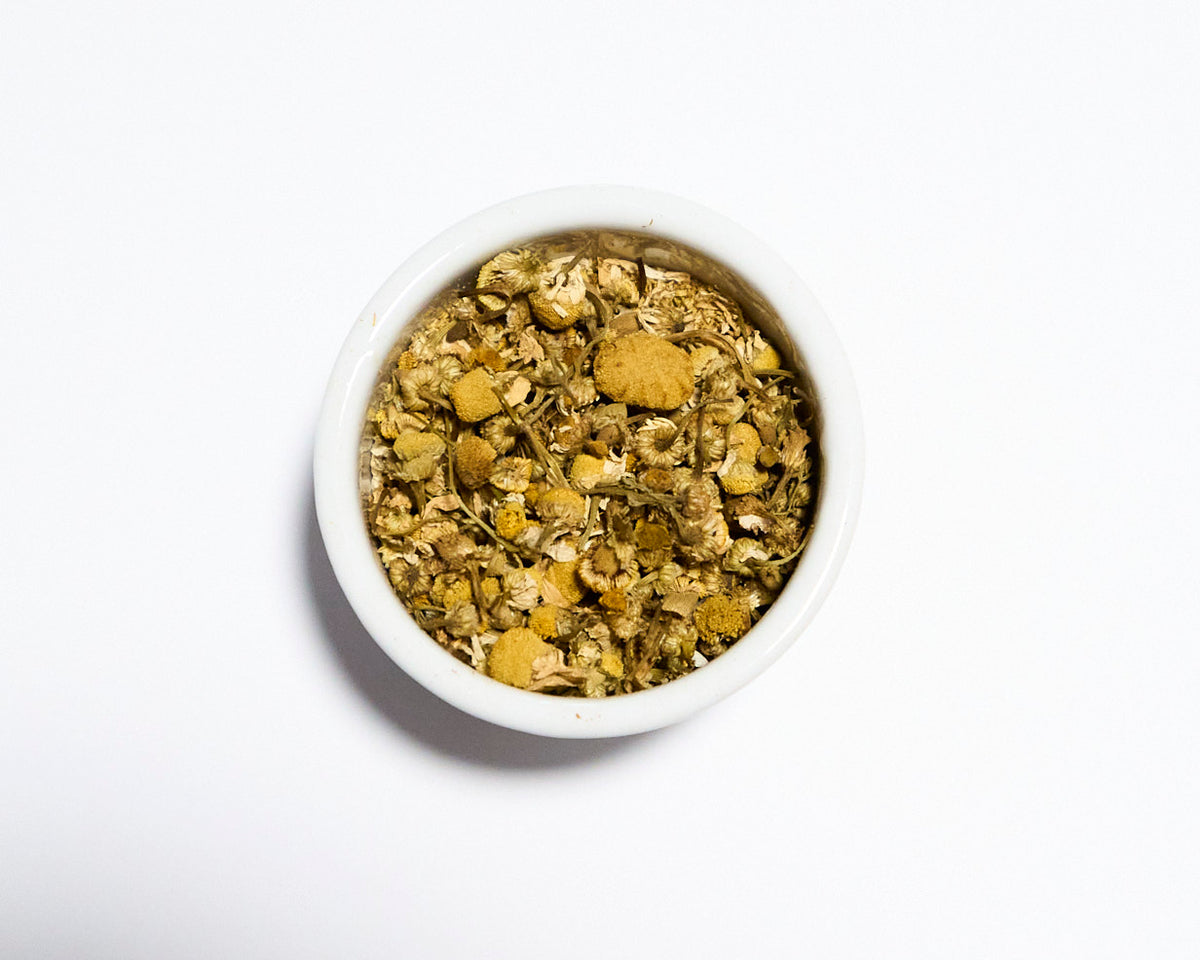 white bowl containing chamomile tea with white background