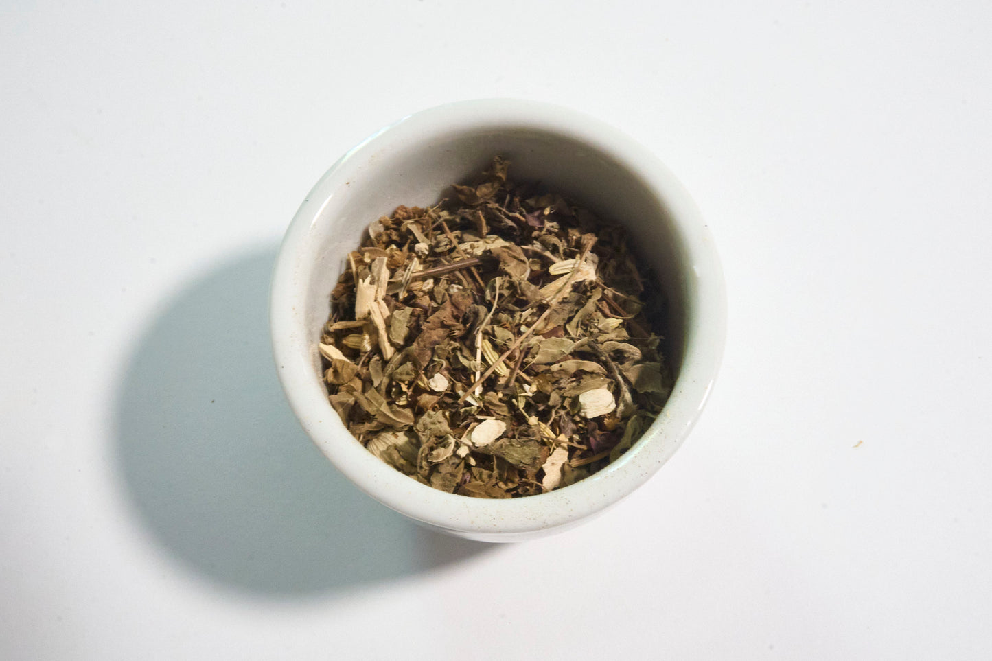 White bowl filled with dried herbs on a white background