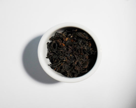 White bowl filled with GABA Oolong black tea leaves on a white background