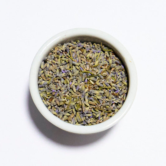 White bowl filled with dried lavender flowers on a white background