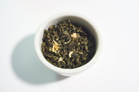 White bowl filled with green tea leaves on a white background