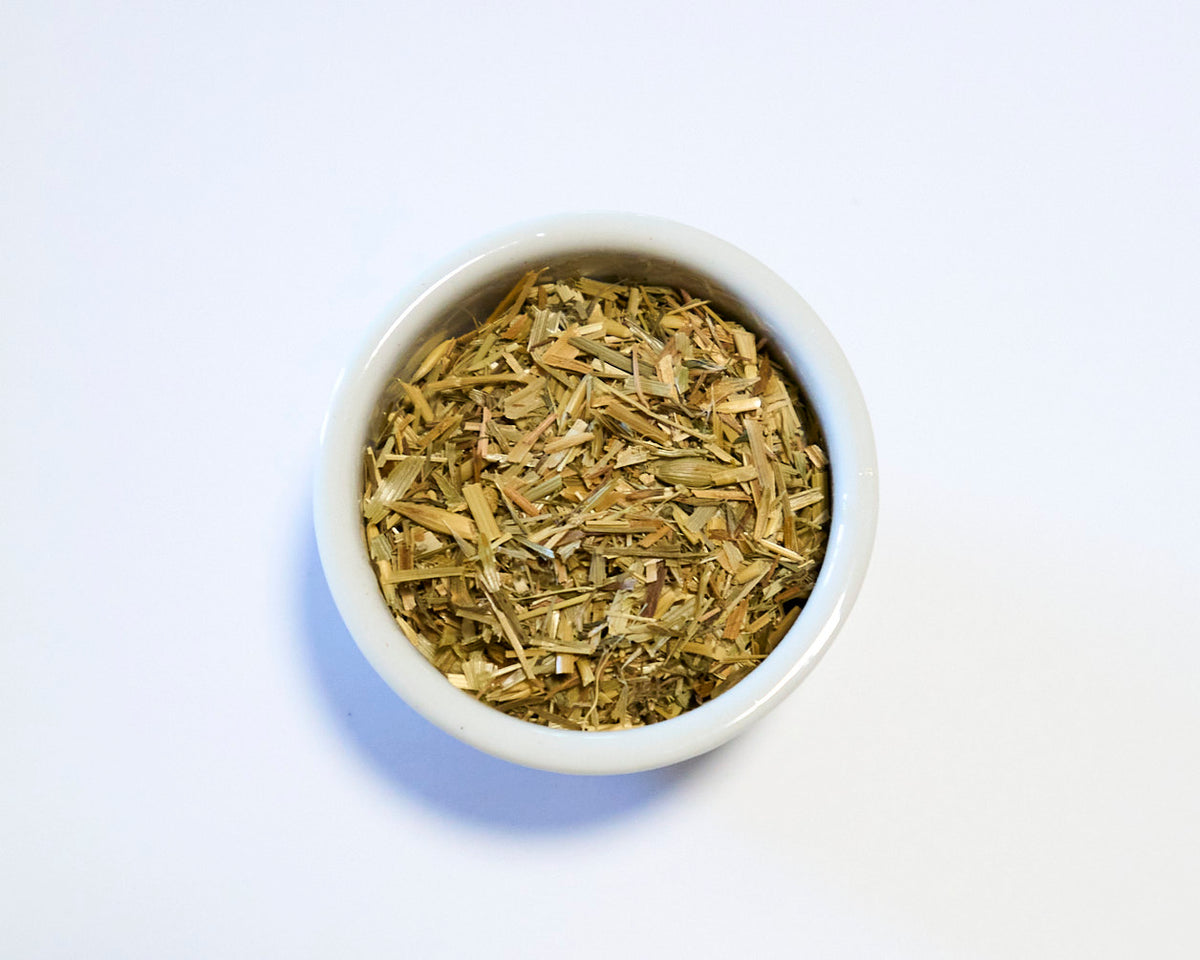 white bowl holding dried oatstraw with white background