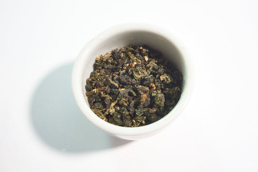 White bowl filled with green tea leaves on a white background