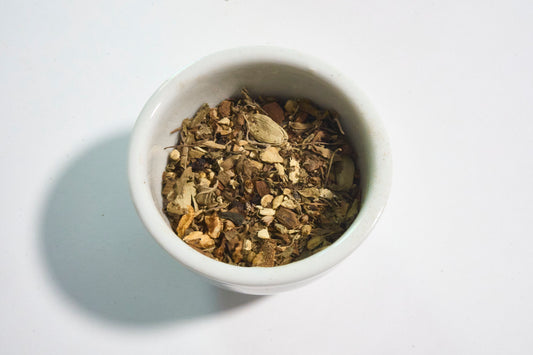 White bowl filled with dried herbs on a white background