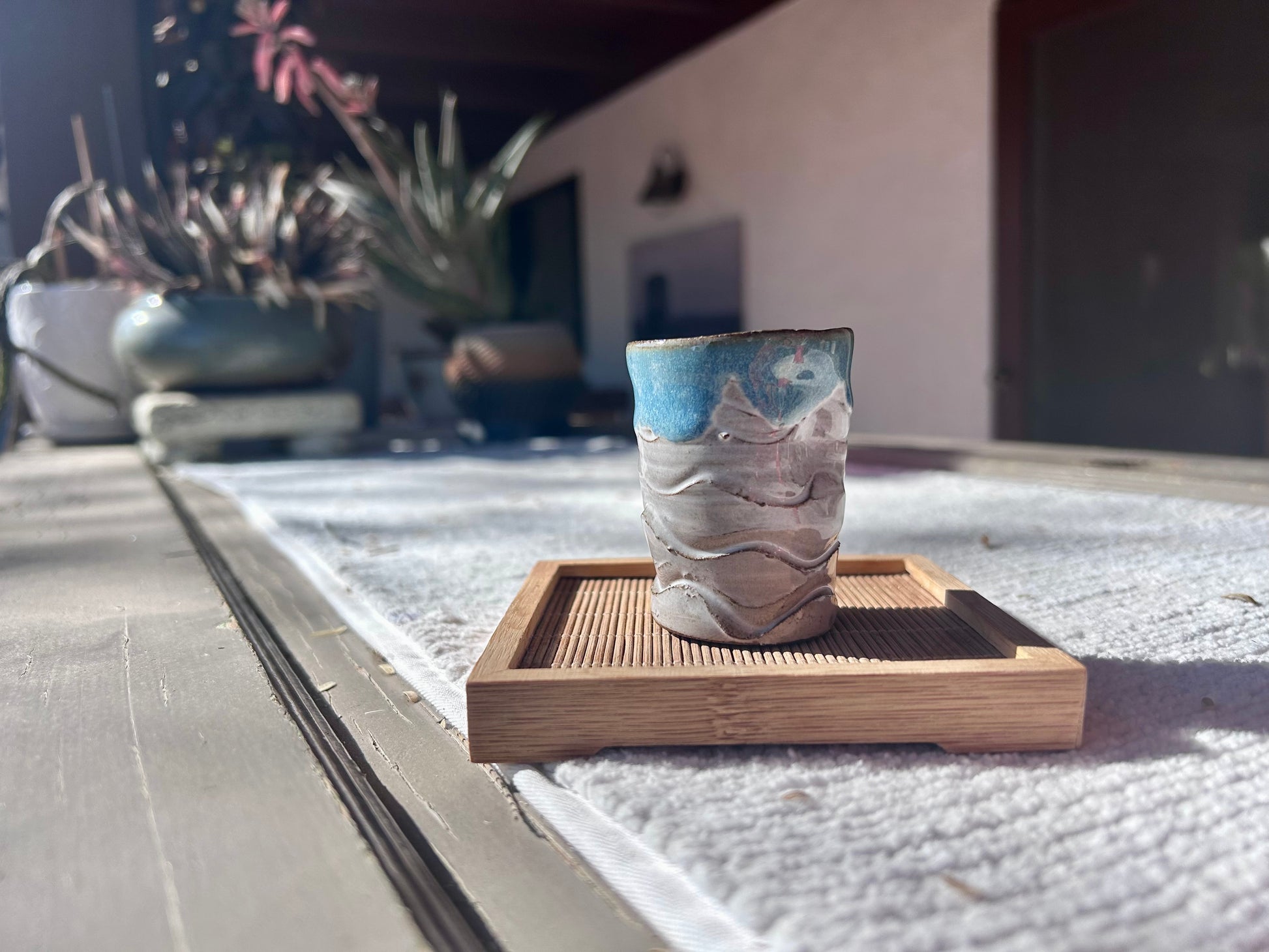 Ceramic cup with blue interior on a wooden coaster outdoors