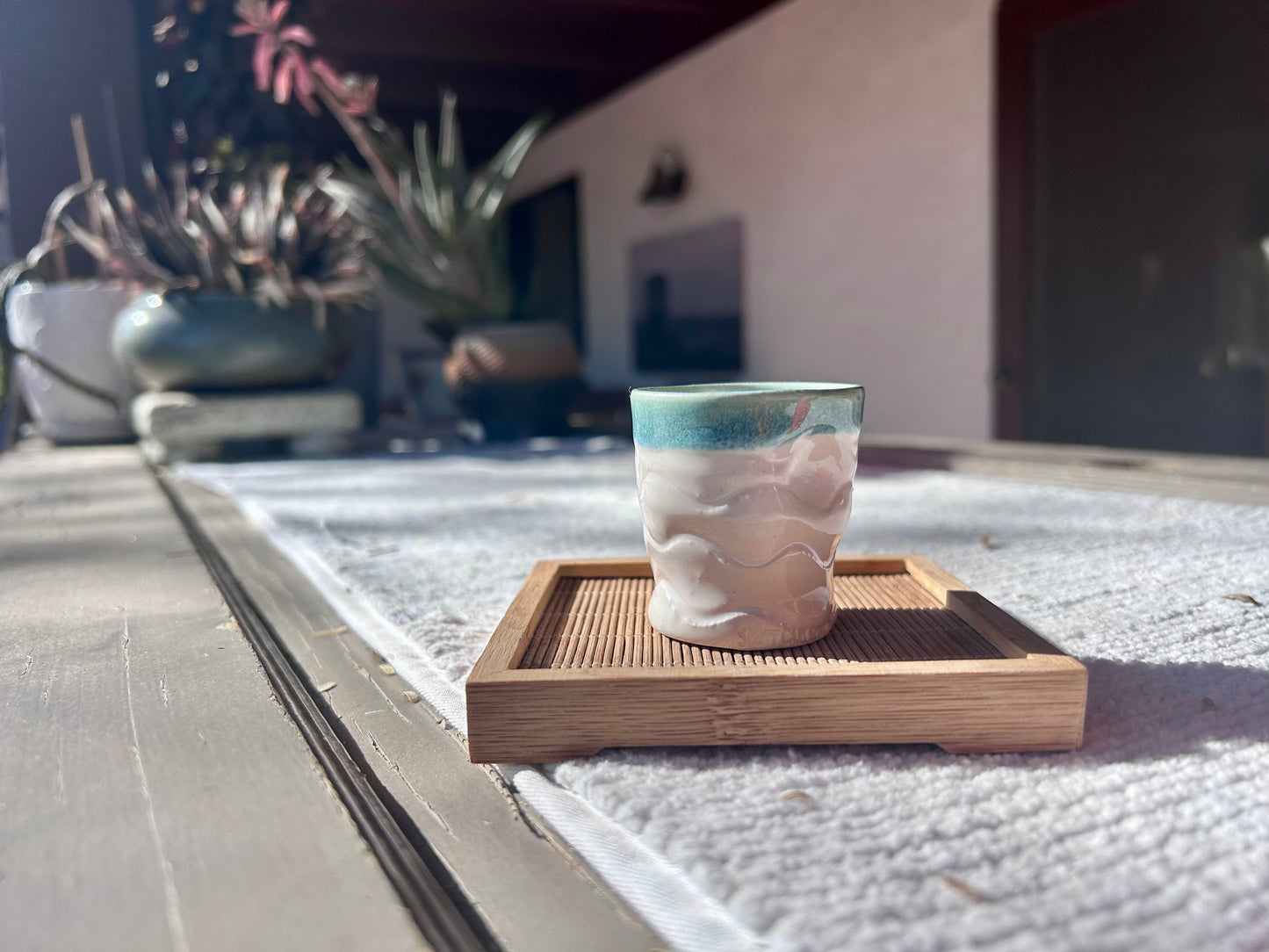 Ceramic cup with textured design on a wooden coaster outdoors