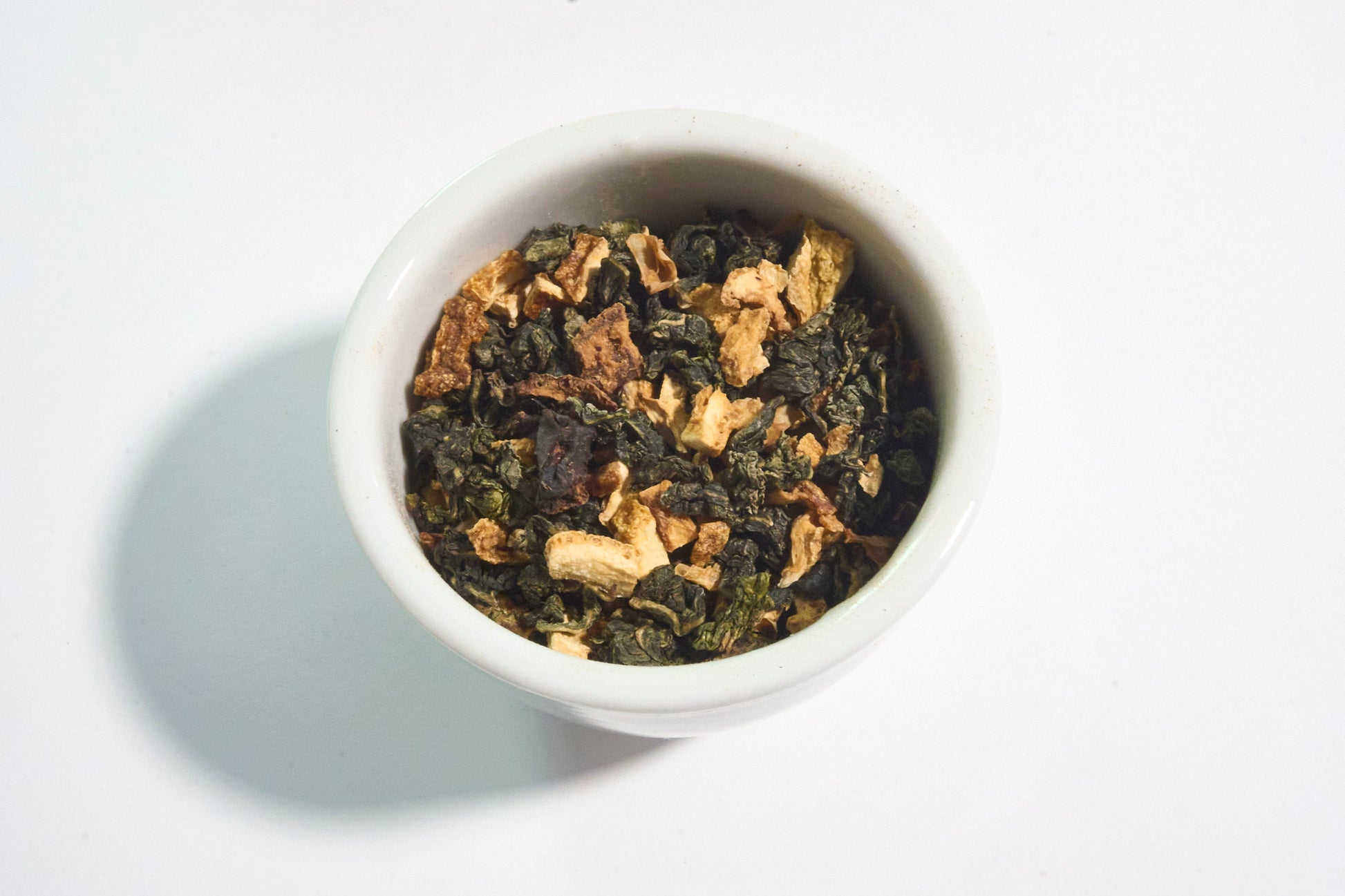 White bowl filled with dry tea leaves on a white background