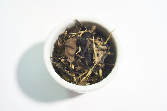 White bowl filled with dried tea leaves on a white background
