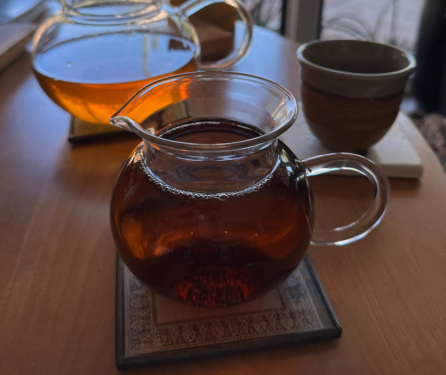 black teas from tea & hammock displayed in clear teapots on wooden table with one green and beige teacup in the background
