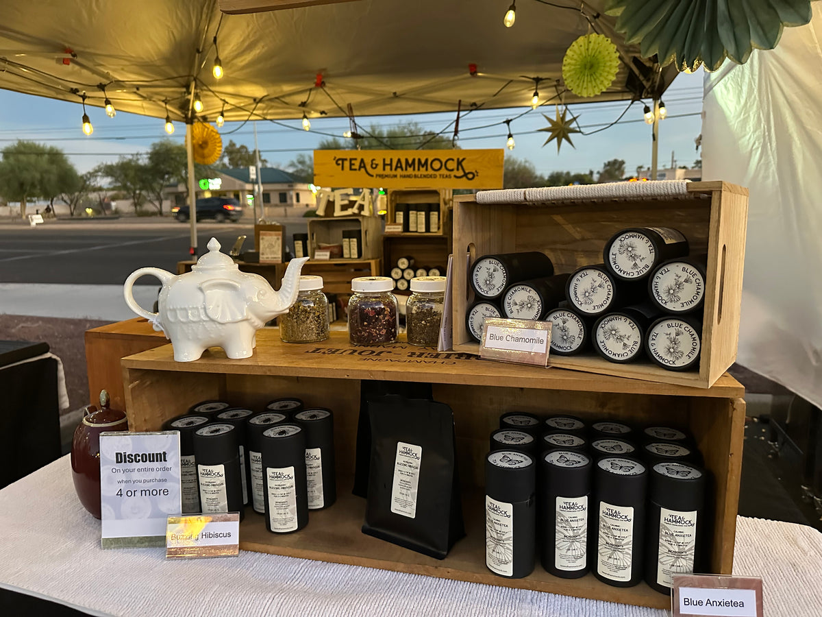 tucson outdoor evening farmers market tea & hammock booth display with twinkle lights and wide variety of local tucson teas tea samples for tasting and smelling and reclaimed unique teaware