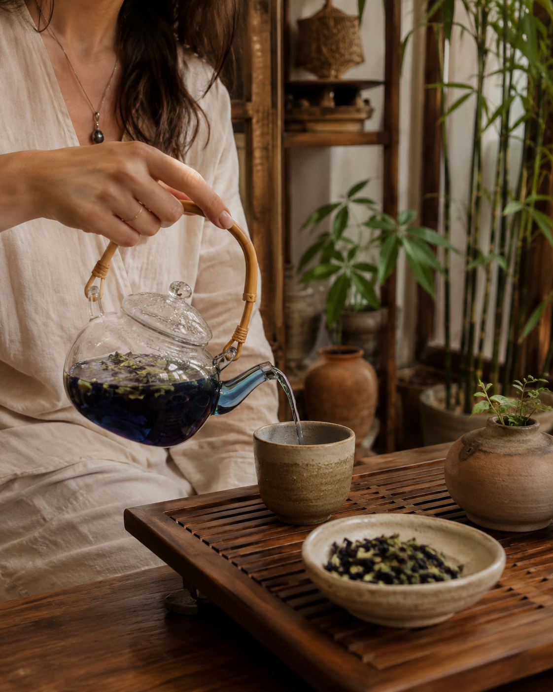 a woman in a zen kitchen pours blue butterfly peaflower tea into a beautiful teacup 